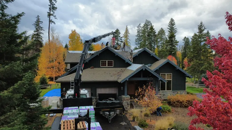 Drone view of an asphalt shingle roof surrounded by autumn trees in the Flathead Valley