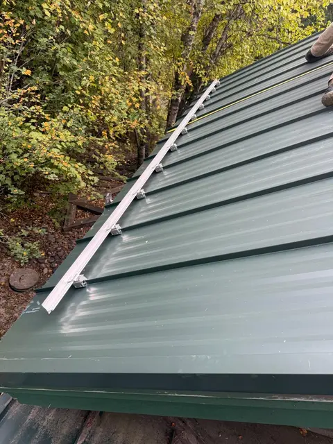Green standing seam metal roof panels on a sloped residential roof